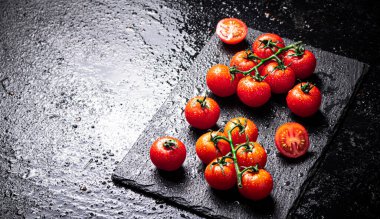 Taş bir tahtanın dalındaki taze domatesler. Siyah bir arka planda. Yüksek kalite fotoğraf