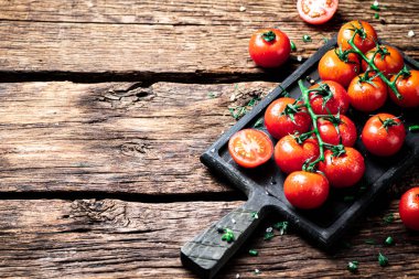 Kesme tahtasındaki dalda taze domatesler. Ahşap bir arka planda. Yüksek kalite fotoğraf