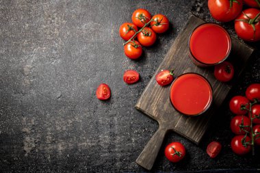 Kesme tahtasındaki bardakta domates suyu. Siyah bir arka planda. Yüksek kalite fotoğraf