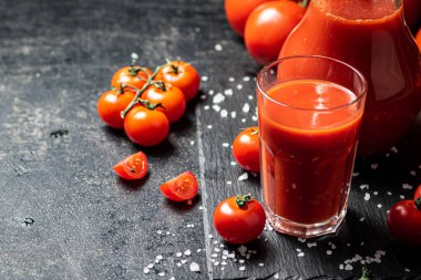 Taş bir tahtada tuz parçalarıyla domates suyu. Siyah bir arka planda. Yüksek kalite fotoğraf