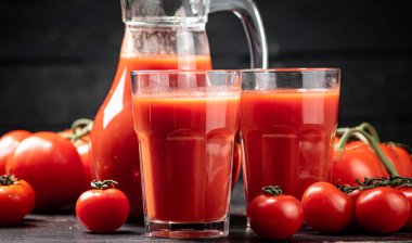 Masadaki olgun domateslerin suyu. Siyah tahta bir arka planda. Yüksek kalite fotoğraf