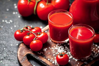 Kesme tahtasında bir bardak domates suyu. Siyah bir arka planda. Yüksek kalite fotoğraf