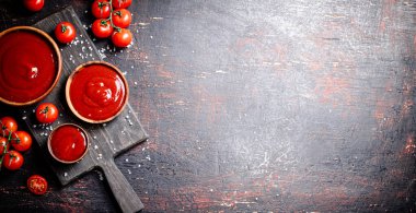 Tahta kesme tahtasında tuz parçalarıyla domates sosu. Karanlık bir arka plana karşı. Yüksek kalite fotoğraf
