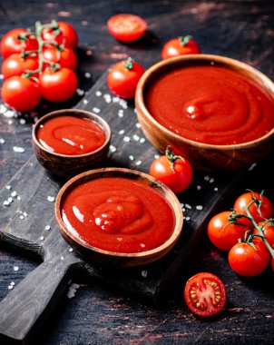 Tahta kesme tahtasında tuz parçalarıyla domates sosu. Karanlık bir arka plana karşı. Yüksek kalite fotoğraf