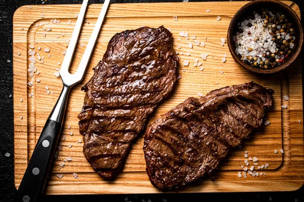 stock image Fresh grilled steak on a spice cutting board. On a black background. High quality photo