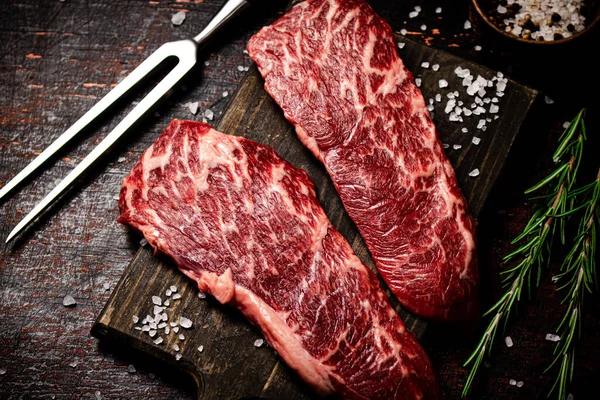 Rohe Steaks Auf Einem Holzschneidebrett Mit Gewürzen Auf Rustikalem Dunklem — Stockfoto