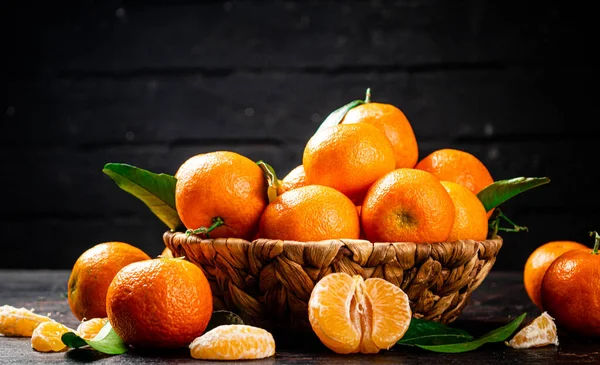 stock image Fresh tangerines with leaves in a basket. Against a dark background. High quality photo