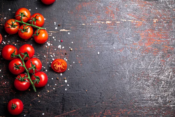 stock image A branch of fresh tomatoes with pieces of salt. Against a dark background. High quality photo