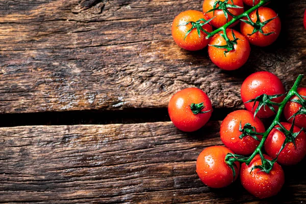 stock image Fresh tomatoes on a branch on the table. On a wooden background. High quality photo