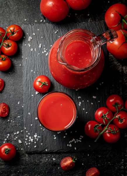 stock image Tomato juice on a stone board with pieces of salt. On a black background. High quality photo