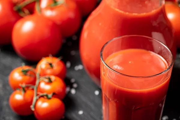 Tomato juice on a stone board with pieces of salt. On a black background. High quality photo