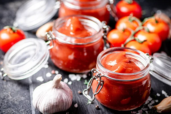 Tomato Sauce Glass Jars Stone Board Spices Black Background High — Stockfoto
