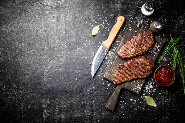 木製のまな板でステーキをグリルします 黒を背景に 高品質の写真 ロイヤリティフリーのストック画像