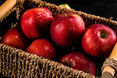 Ripe red apples in a basket. On a black background. High quality photo