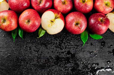 Whole and pieces of red apple with leaves. On a black background. High quality photo