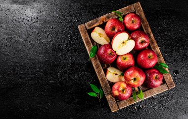 Pieces and whole red apples on a wooden tray. On a black background. High quality photo