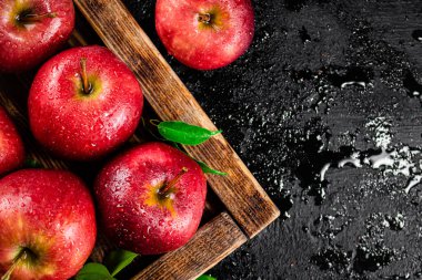 Pieces and whole red apples on a wooden tray. On a black background. High quality photo