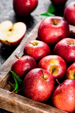 Ripe red apples on a wooden tray. On a black background. High quality photo