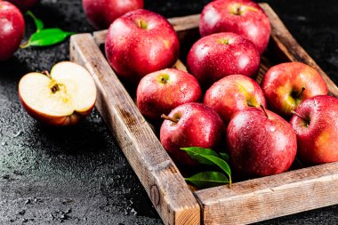 Ripe red apples on a wooden tray. On a black background. High quality photo