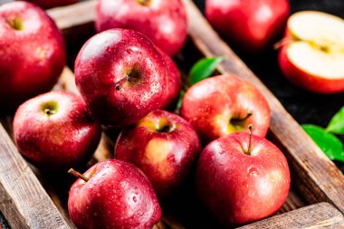 Red apples on a wooden tray. On a black background. High quality photo