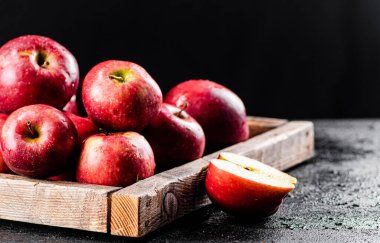 Ripe red apples on a wooden tray. On a black background. High quality photo