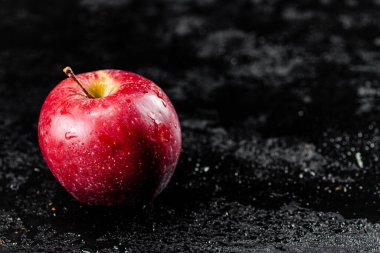 One red apple on the table. On a black background. High quality photo