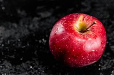 One red apple on the table. On a black background. High quality photo