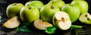 Pieces and a whole apple with leaves on the table. On a black background. High quality photo