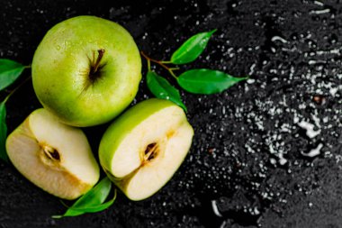 Pieces and a whole apple with leaves on the table. On a black background. High quality photo