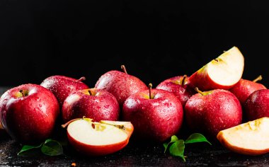Half and whole apples with leaves on the table. On a black background. High quality photo