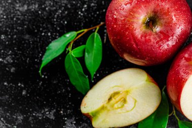 Half and whole apples with leaves on the table. On a black background. High quality photo