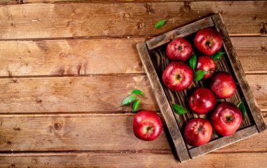 Fresh apples with leaves on the tray. On a wooden background. High quality photo