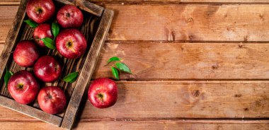 Fresh apples with leaves on the tray. On a wooden background. High quality photo