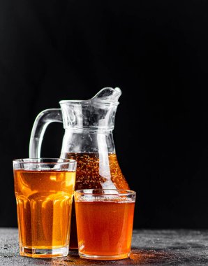 Apple juice in a jug and glasses with air bubbles. On a black background. High quality photo