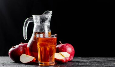 Juice from ripe apples in a jug and a glass on the table. On a black background. High quality photo