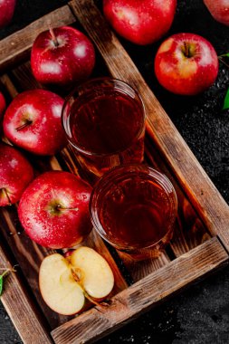Apple juice on a wooden tray. On a black background. High quality photo