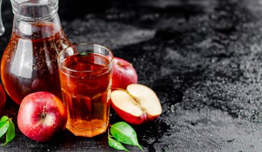 Apple juice in a jug and a glass on the table. On a black background. High quality photo