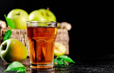A glass of green apple juice with leaves on the table. On a black background. High quality photo