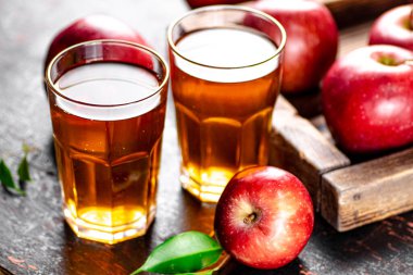 A glass of apple juice on the table. On a rustic dark background. High quality photo