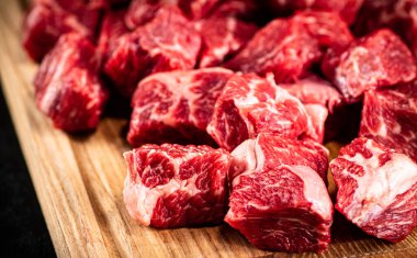 Raw pieces of beef on a wooden cutting board. On a black background. High quality photo