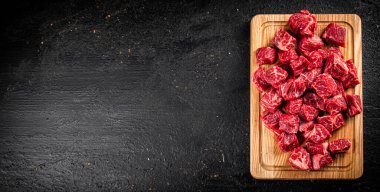 Raw pieces of beef on a wooden cutting board. On a black background. High quality photo