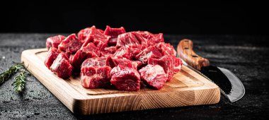 Chopped raw beef on a cutting board with rosemary and a knife. On a black background. High quality photo