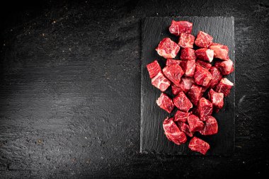 Pieces of raw beef on a stone board. On a black background. High quality photo