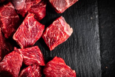Pieces of raw beef on a stone board. On a black background. High quality photo