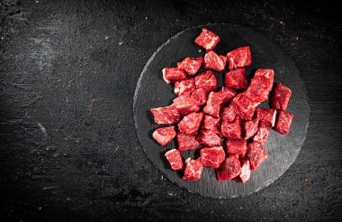 Pieces of raw beef on a stone board. On a black background. High quality photo