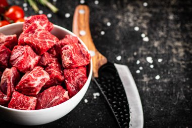 Sliced pieces of raw beef in a bowl. On a black background. High quality photo