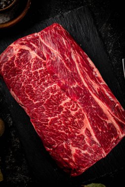 A piece of raw beef on a stone board. On a black background. High quality photo