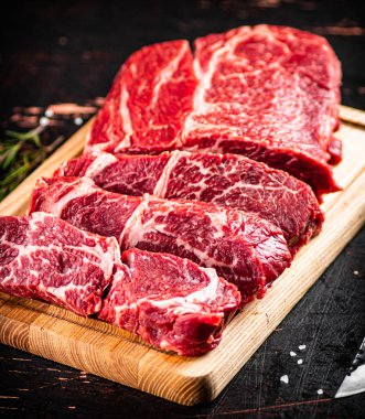 Beef raw cut on a cutting board. On a rustic dark background. High quality photo