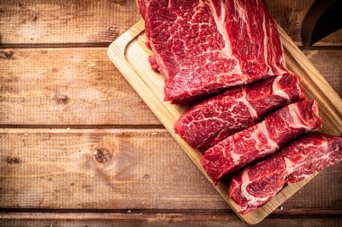 Raw beef on a cutting board with a knife. On a wooden background. High quality photo