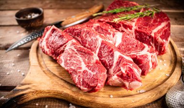 Raw beef on a cutting board with rosemary and spices. On a wooden background. High quality photo